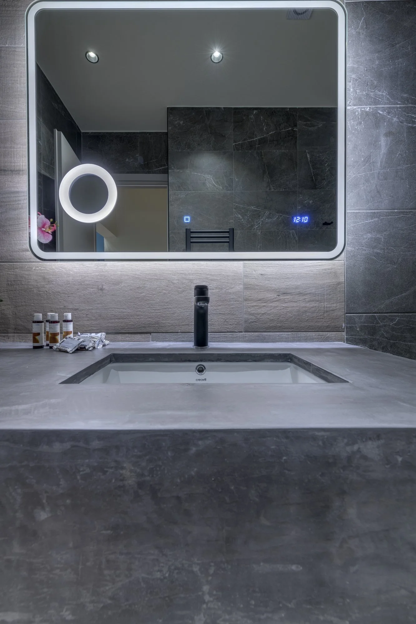 Bathroom basin with round mirror and tiled wall