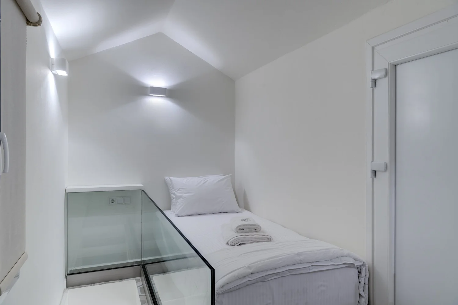 Detail of bedroom three with the made single bed and wall light