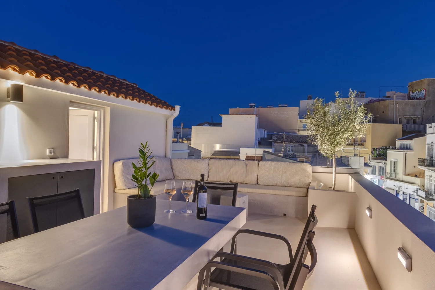 Upper terrace dining table at night overlooking Ermoupolis