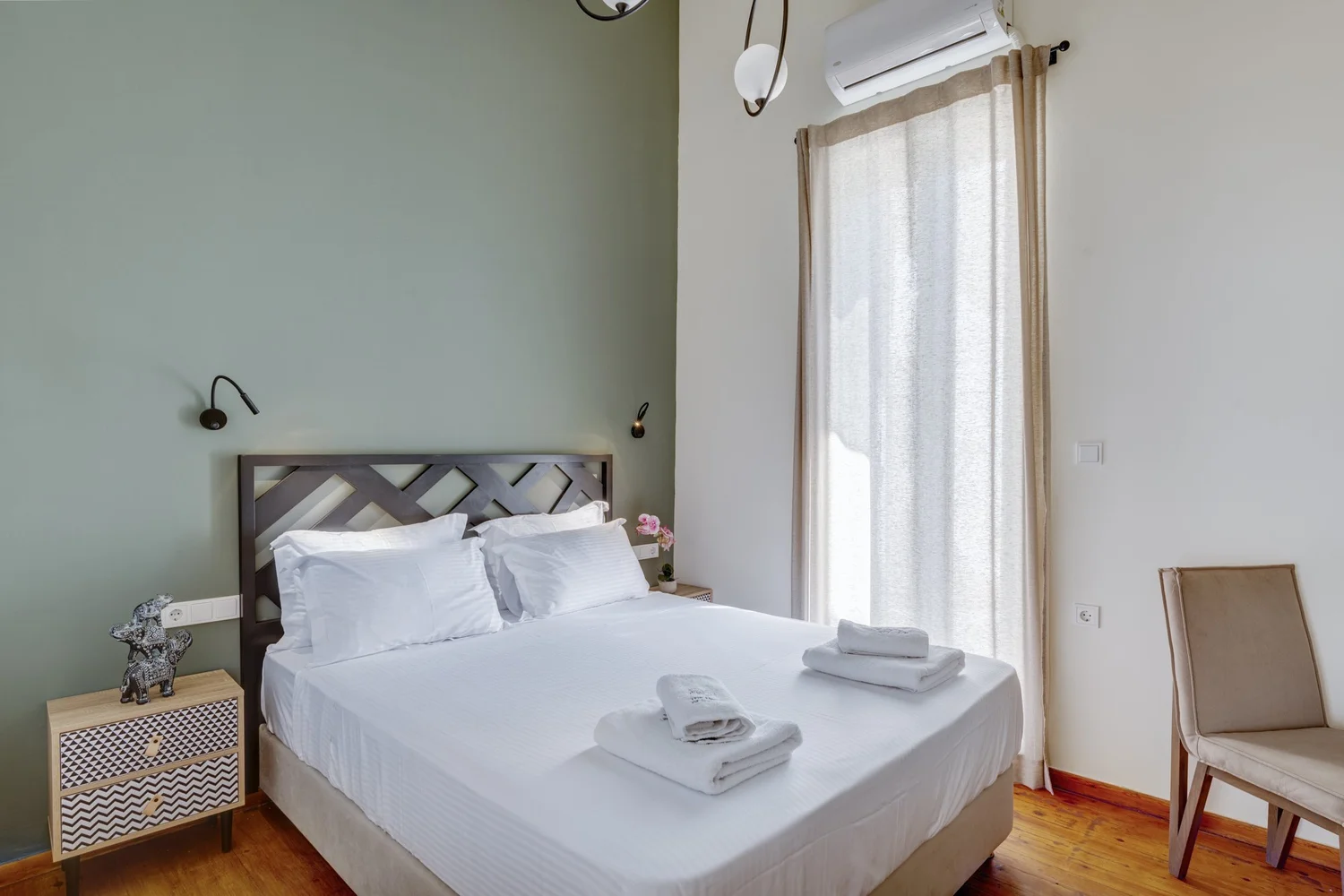 Bedroom one with green feature wall, queen bed and white linen